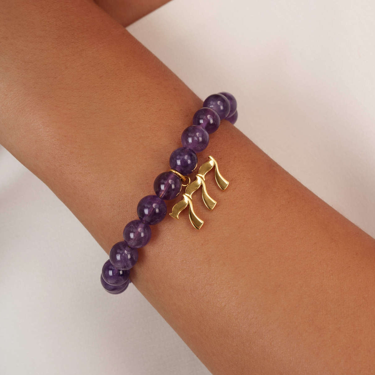 High quality purple amethyst beads with dangling 777 gold charm on wrist