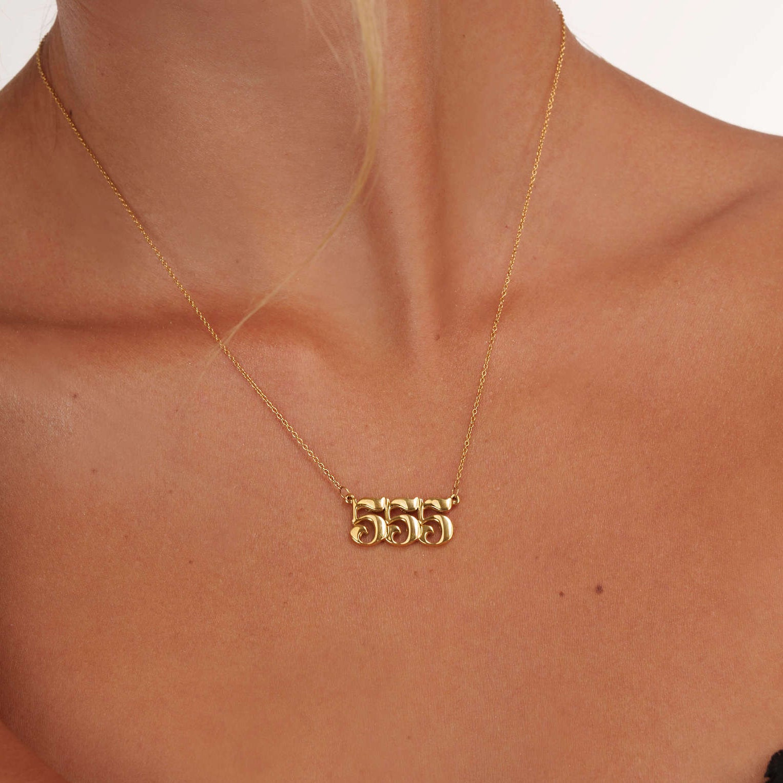 woman wearing gold 555 necklace with unique design