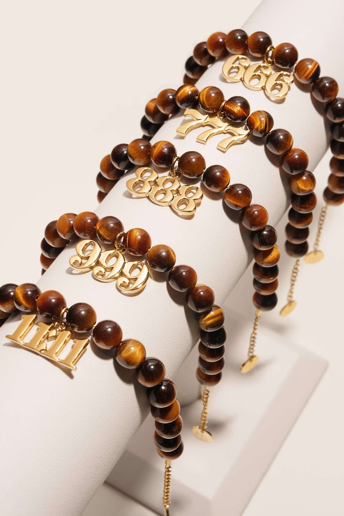 layered bracelets with brown and black tigers eye  gemstone beads and dangling angel number charms 666 777 888 999 11:11