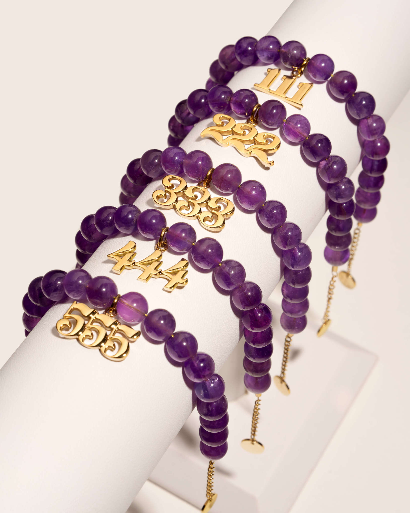 bracelets stacked that have deep purple amethyst beads and dangling angel number charms 111 222 333 444 555