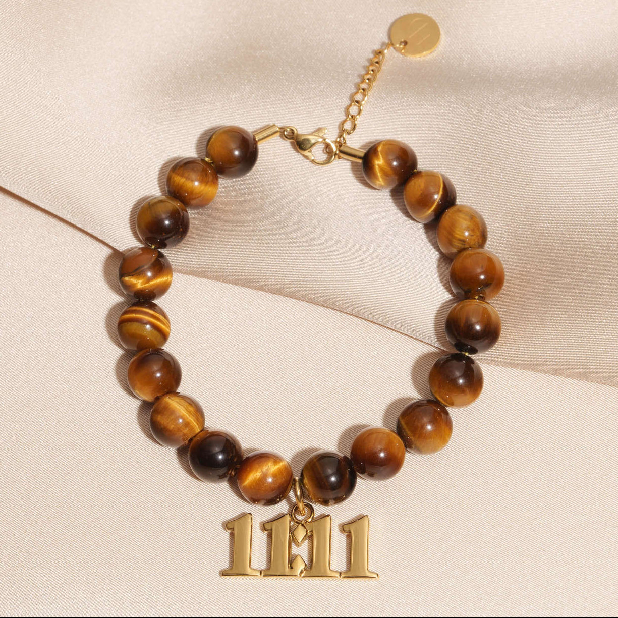 11:11 Gold charm on beaded Tigers Eye bracelet laying on silk
