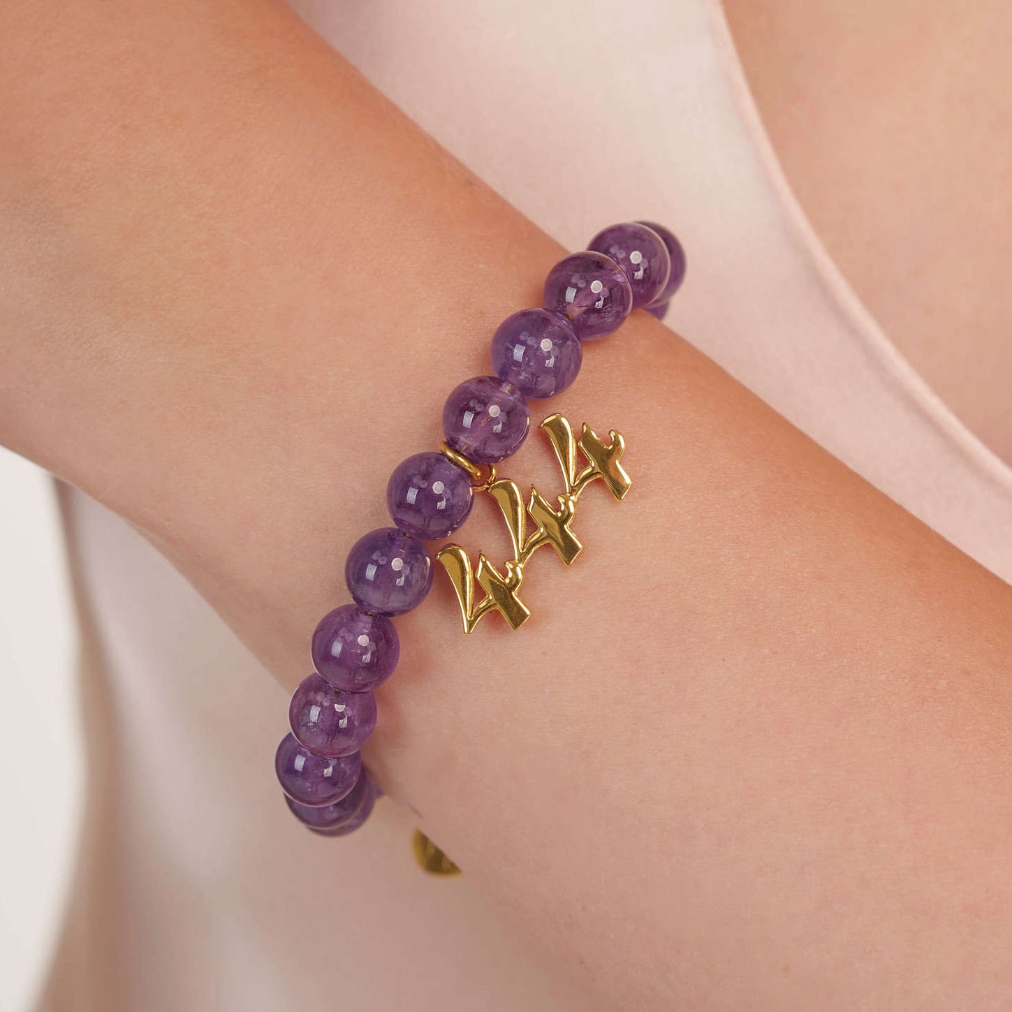 High quality purple amethyst beads with dangling 444 gold charm on wrist

